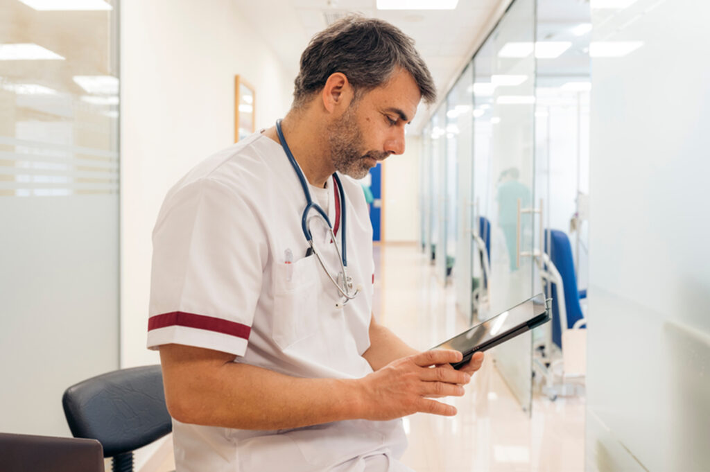 Das Bild zeigt einen Mediziner, der auf einem Tablet elektronische Patientendaten einsieht. 